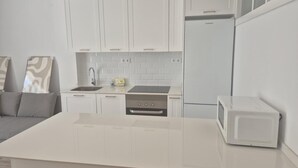 Eine moderne Küche mit weißen Schränken, einem Einbauherd, einer Spüle und einem Kühlschrank.