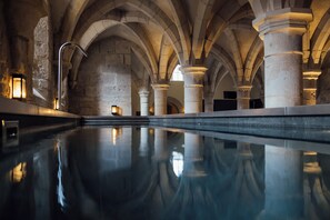 A swimming pool with stone arches and columns, reflecting the pool's surface. - Les Sources de Vougeot (Gilly-lès-Cîteaux)