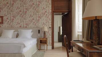 A hotel room with a bed, bedside table, lamp, chair, desk, and a mirror.