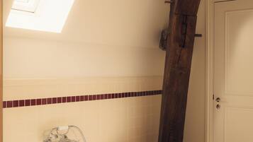A bathroom with a freestanding bathtub, a small wooden stool, and a window above the tub.