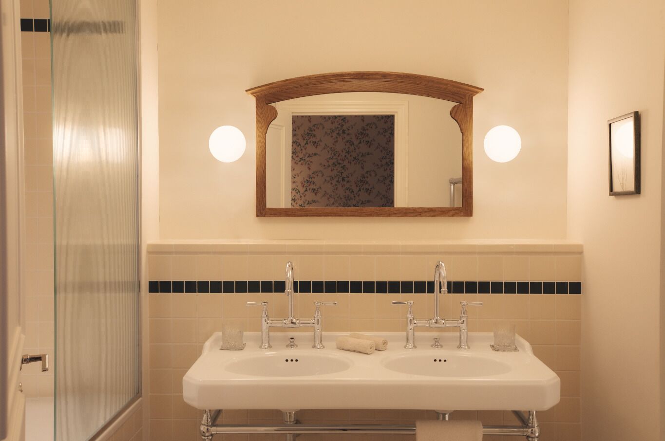 A bathroom with a double sink, a mirror, and a shower.