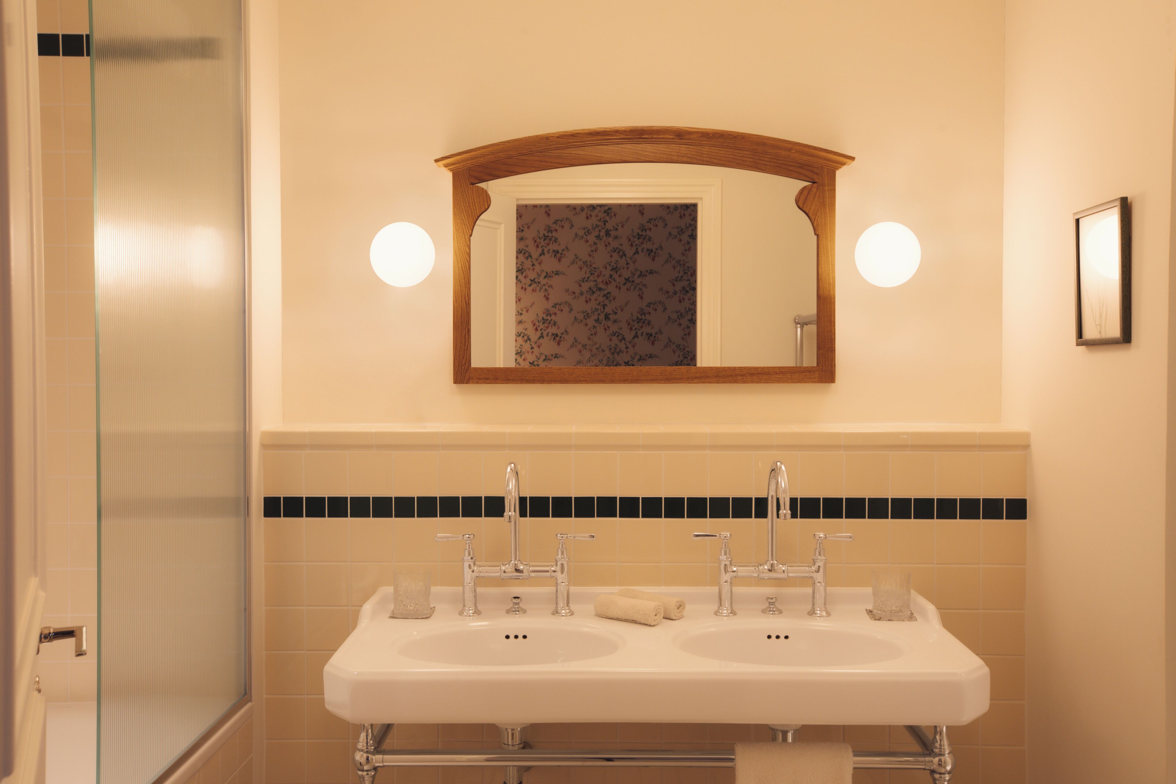 A bathroom with two sinks, a mirror, and a glass shower enclosure.