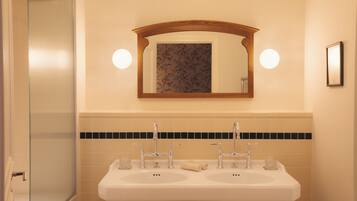 A bathroom with two sinks, a mirror, and a glass shower enclosure.