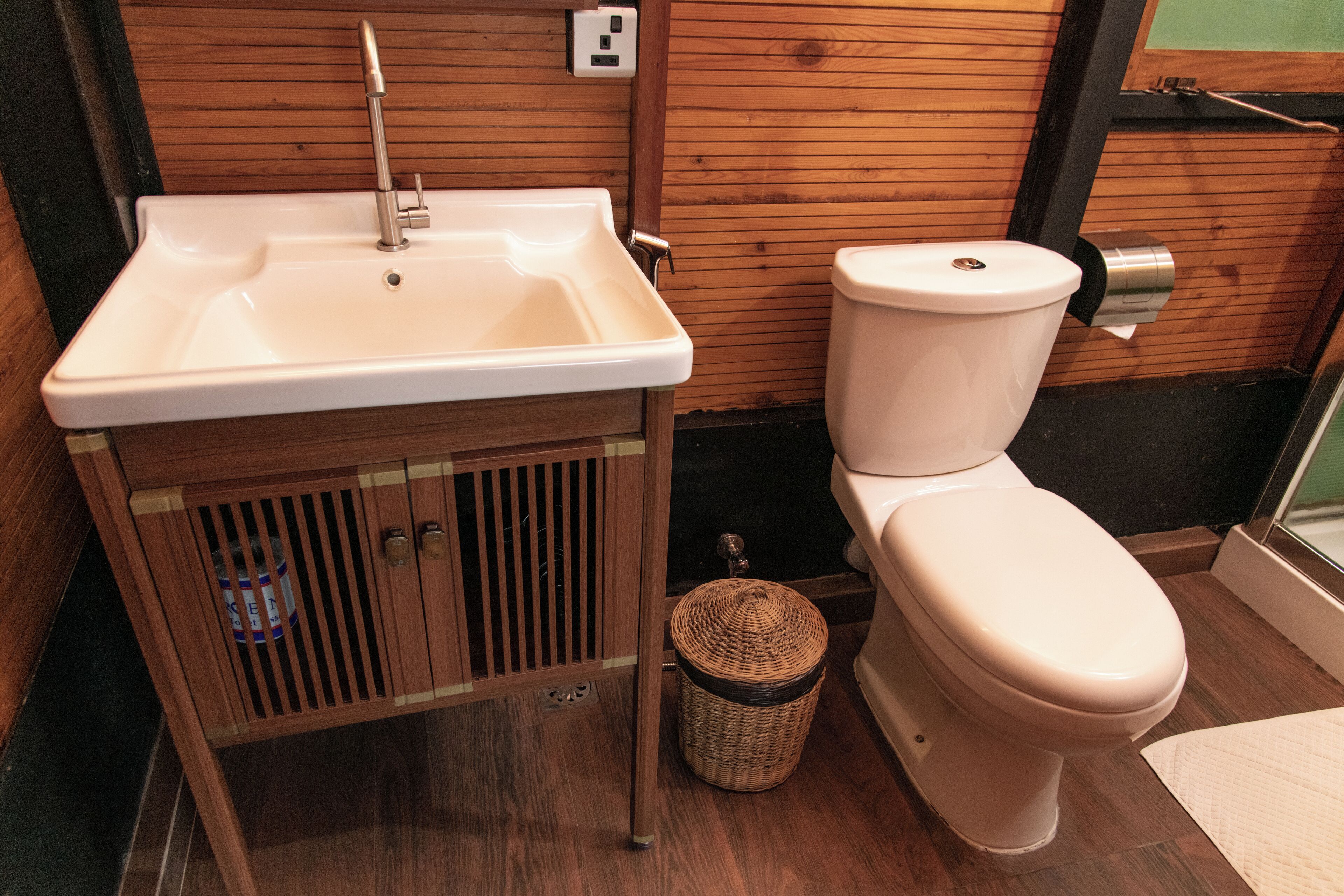 A bathroom with a wooden vanity, a white sink, and a toilet.