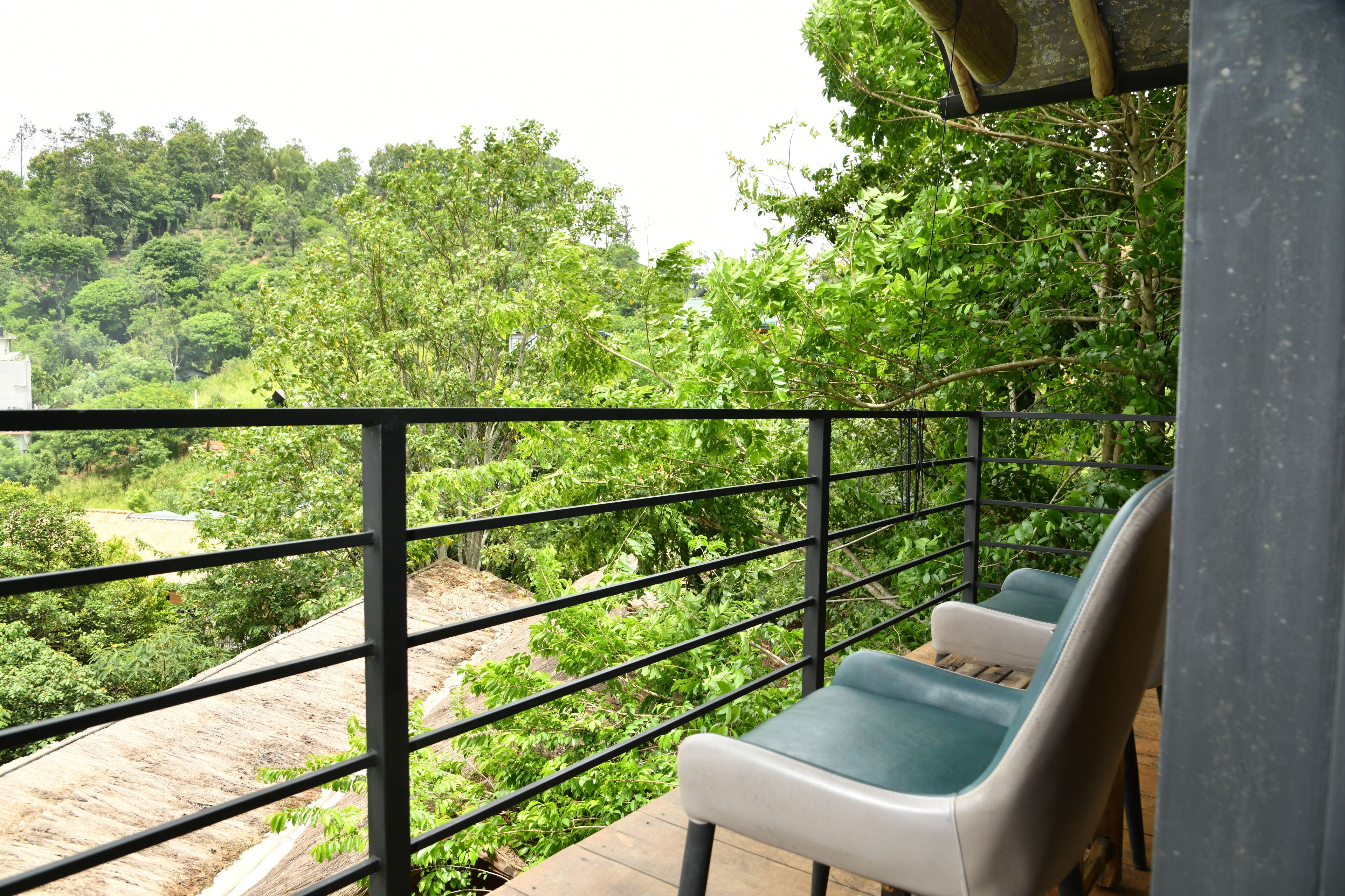 Un balcon doté d’une rambarde en métal, donnant sur un paysage verdoyant et luxuriant.