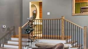 A staircase with wooden railings and steps, a potted plant, and a cushioned bench.