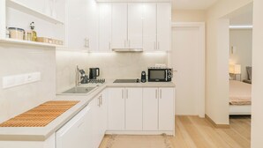 A compact kitchen with white cabinets, a microwave, a coffee maker, and a sink. - Plantaea Studio - Athens Escape  (Athens)