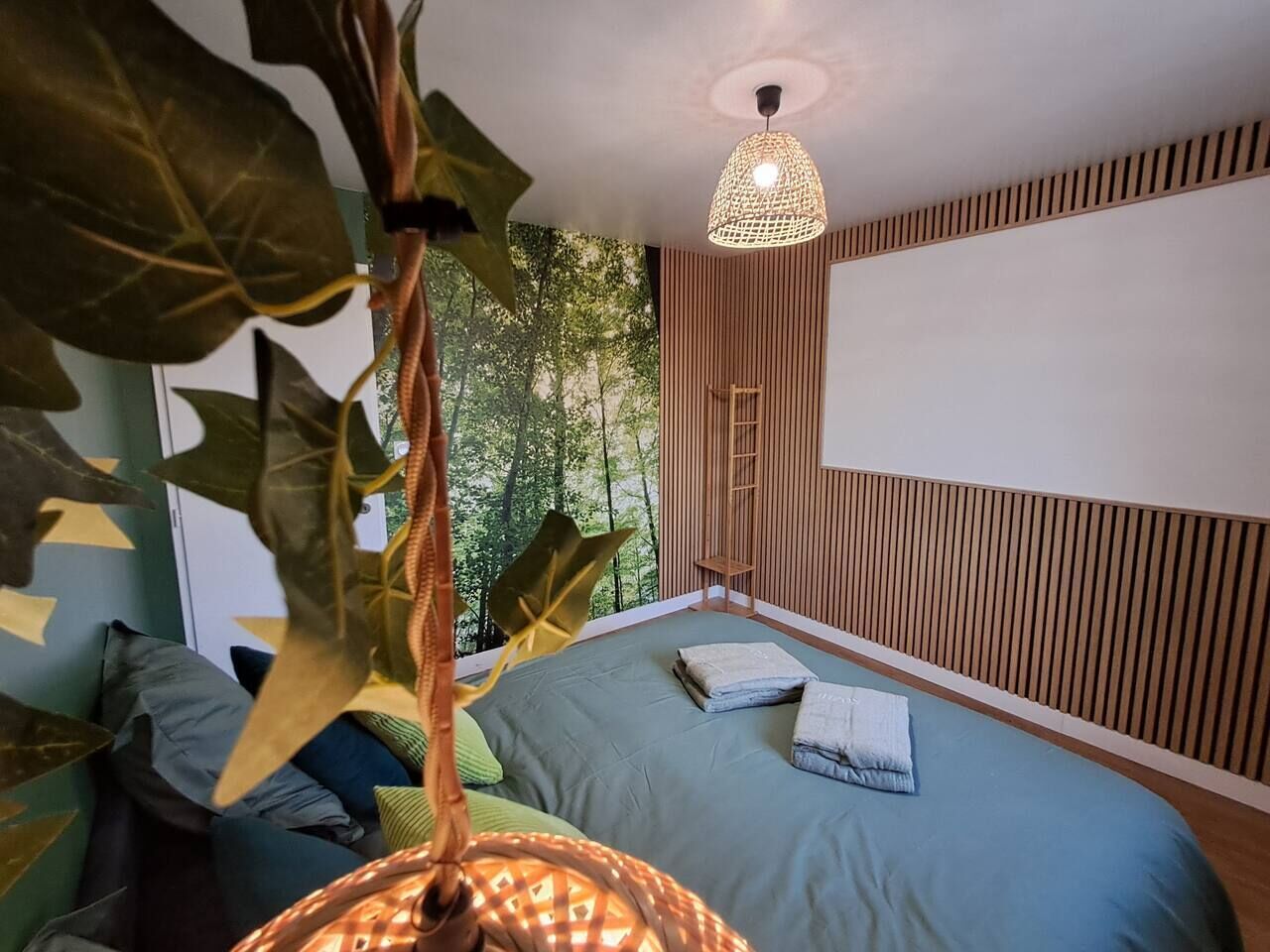 Et moderne soveværelse med seng, hængende plante og loftlampe.