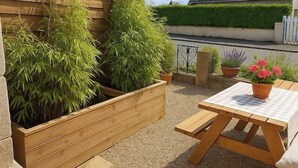 Un patio con fioriere in legno, un tavolo e una sedia.