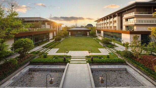 Un complejo moderno de edificios con un patio central, senderos y zonas verdes circundantes.