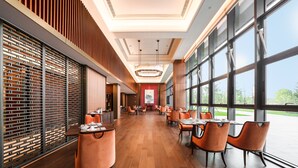 Un restaurante espacioso con techos altos, ventanas amplias y mobiliario moderno.