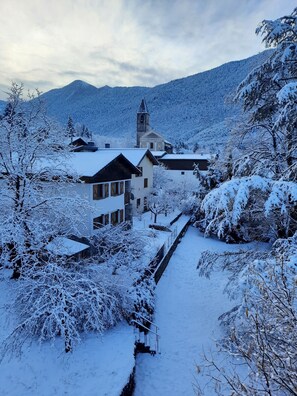 Ein verschneites Dorf mit Kirche, Häusern und einem Berg im Hintergrund.