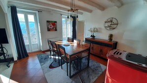 Un comedor con una mesa y sillas de madera, un armario rojo y vistas a través de amplios ventanales.