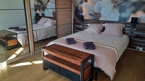 Un dormitorio moderno con una cama grande, una mesita de noche de madera y un espejo.