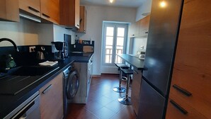 Una cocina con armarios de madera, lavadora, cafetera y refrigerador.
