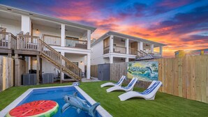 A two-story house with a swimming pool, a wooden deck, and a mural on the fence.