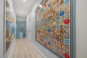 Käytävällä on Scrabble-peli, taulu ja ikkuna, jossa on verhot.