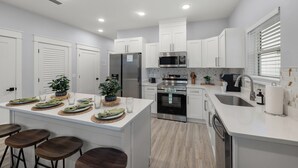 A modern kitchen with white cabinets, stainless steel appliances, and a central island with bar stools.