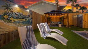 A backyard with a mural, outdoor seating, and a wooden fence.