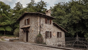 A stone house with a wooden door, a small porch, and a metal fence. - Borgo La Ferriera (Celleno)