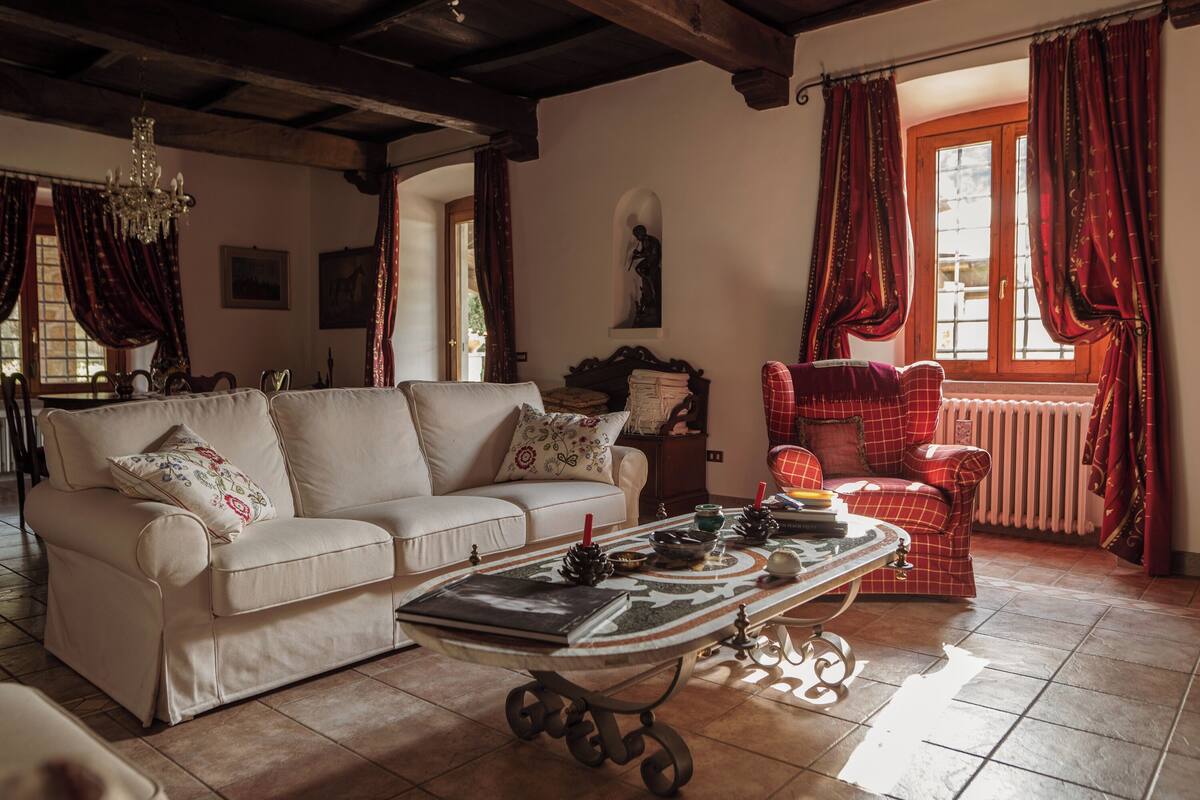 A living room with a white sofa, a coffee table, and a red armchair.