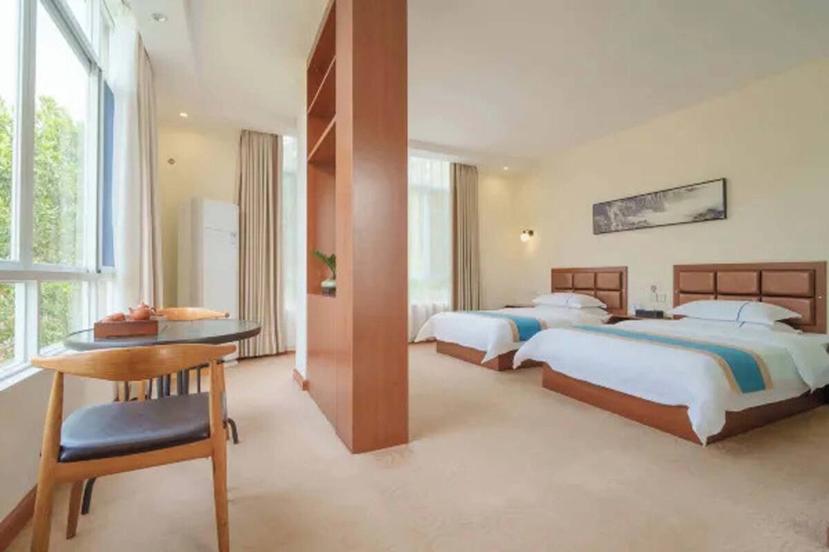 Une chambre d’hôtel avec deux lits, un bureau et une chaise.