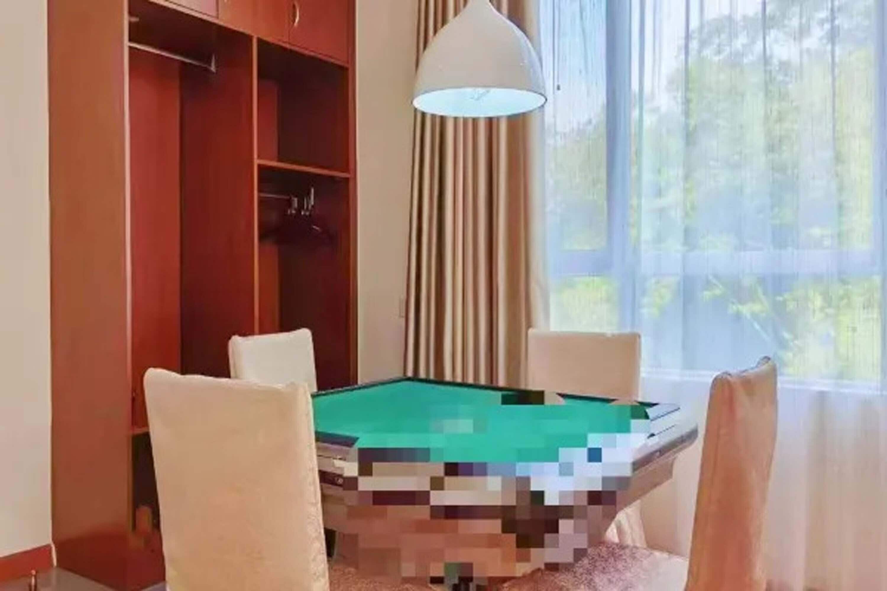 Ein Billardtisch in einem Raum mit Fenster, Vorhängen und einem Holzschrank.