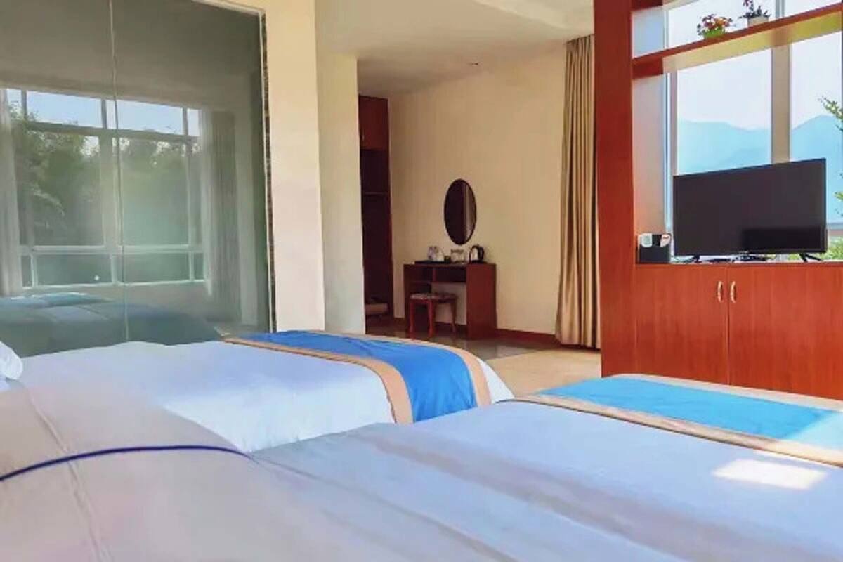 Une chambre d’hôtel avec deux lits, une télévision, un bureau et une fenêtre donnant sur un paysage agréable.