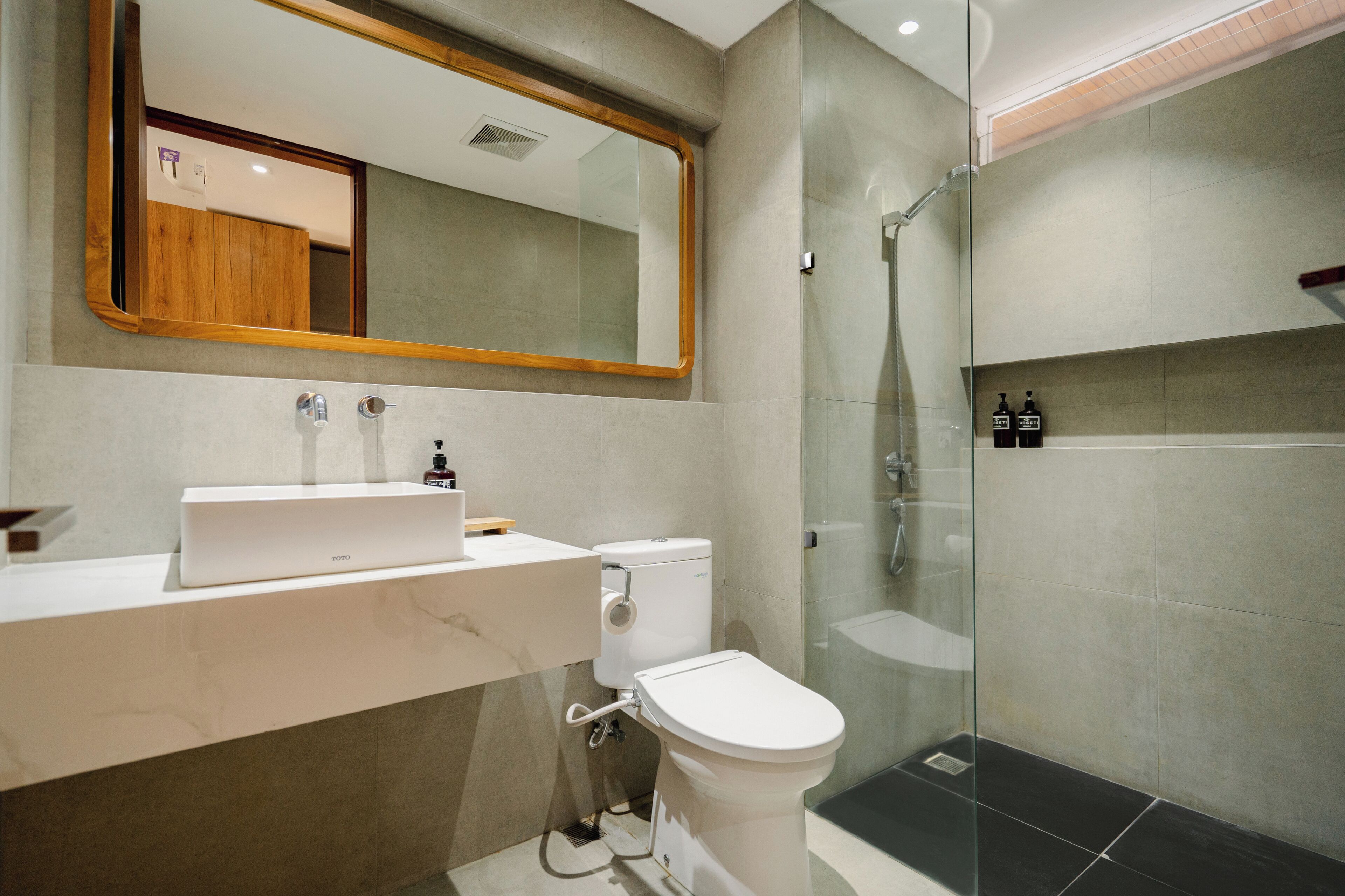 A modern bathroom with a white sink, a toilet, and a glass-enclosed shower.