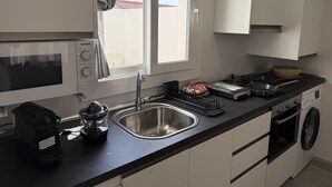 A modern kitchen with a built-in microwave, a stainless steel sink, a coffee maker, and a washing machine. - Apartamento 2B in Malaga (Málaga)