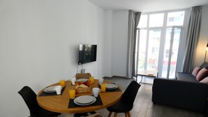 A dining area with a round table, chairs, breakfast items, and a TV on the wall. - Apartamento 1B in Malaga (Málaga)