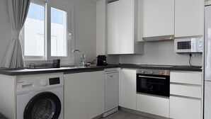 A modern kitchen with a washing machine, dishwasher, oven, and microwave. - Apartamento 1A in Malaga (Málaga)