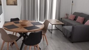 A modern living room with a round wooden dining table, two sofas, and a coffee table. - Apartamento 1A in Malaga (Málaga)