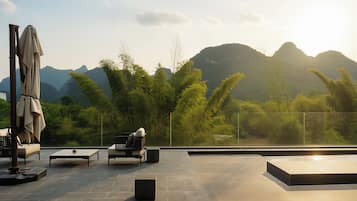 An outdoor terrace with seating, a table, and a view of mountains.