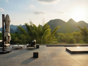 An outdoor terrace with seating, a table, and a view of mountains. - YINGMAN HOTEL (Guilin)