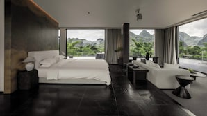 A modern bedroom with a large bed, a sofa, and a view of mountains. - YINGMAN HOTEL (Guilin)