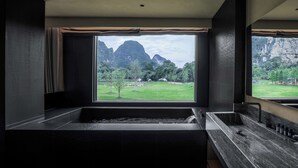 A modern bathroom with a large bathtub and a view of mountains and greenery. - YINGMAN HOTEL (Guilin)