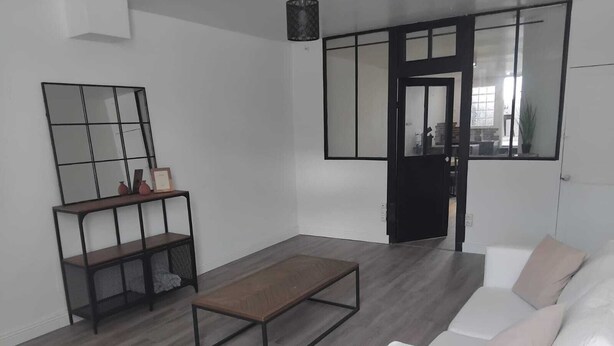 Una sala de estar moderna con un sofá blanco, una mesa de centro de madera y un espejo con marco negro en la pared.