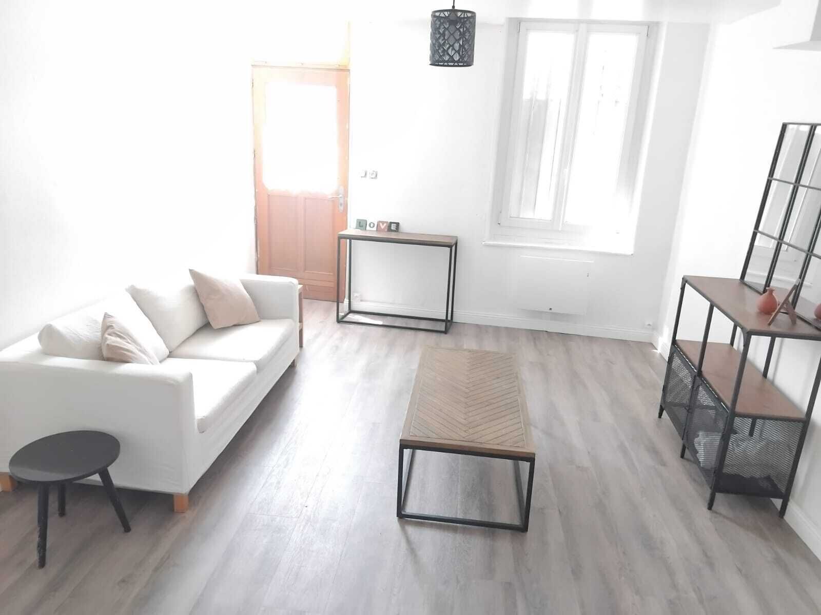 Un salon moderne avec un canapé blanc, une petite table ronde, un banc et une étagère en métal.