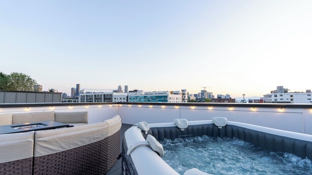 Terraza en la azotea con jacuzzi, zona de estar y vistas al horizonte de la ciudad.