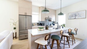 Una cocina moderna con una isla central, electrodomésticos de acero inoxidable y armarios de madera.