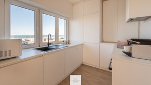 A modern kitchen with a large window, a built-in oven, and a view of the beach. - The Corner Floor, front row sea view and parking (Oostende)