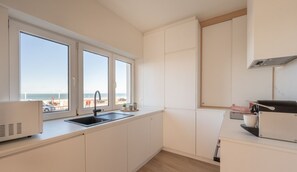 A modern kitchen with a large window, a built-in oven, and a view of the beach. - The Corner Floor, front row sea view and parking (Oostende)