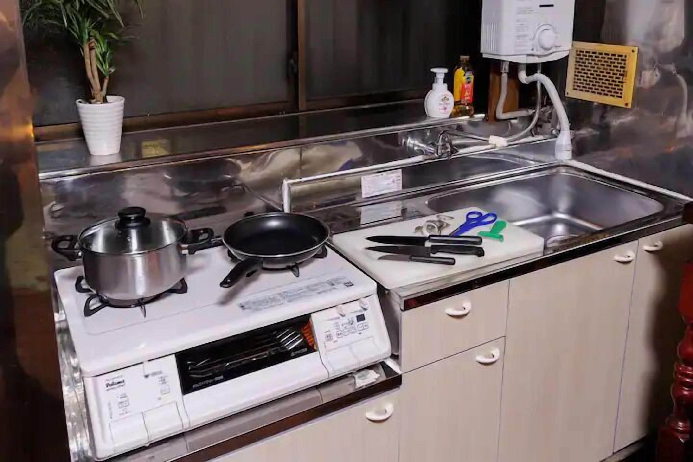 A kitchen with a stove, a sink, and various utensils.