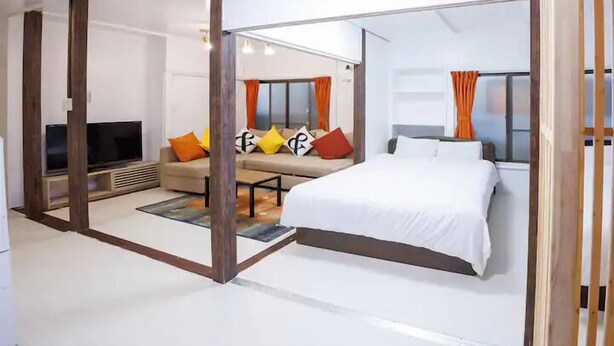 Une chambre d’hôtel moderne avec un grand lit, un canapé, une télévision et une fenêtre avec des rideaux.