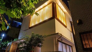 Un bâtiment moderne à deux étages, doté d’un toit plat et d’un balcon avec des lattes de bois verticales.