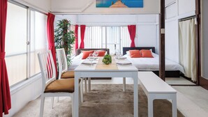 Une chambre d’hôtel moderne, dotée d’un grand lit, d’une table à manger et offrant une vue sur la mer par les fenêtres.