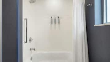 Ein modernes Badezimmer mit Badewanne, Duschkopf und drei Flaschen Shampoo und Conditioner an der Wand.