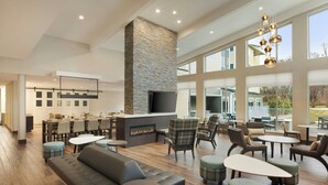 A spacious indoor area with a fireplace, seating arrangements, and large windows. - Residence Inn by Marriott Battle Creek (Battle Creek)