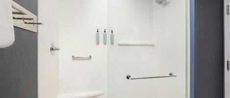 A modern bathroom with a glass shower enclosure, white tiles, and a towel rack.